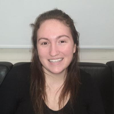 Photo of Hannah Zimmerman in front of a black chair and white background.